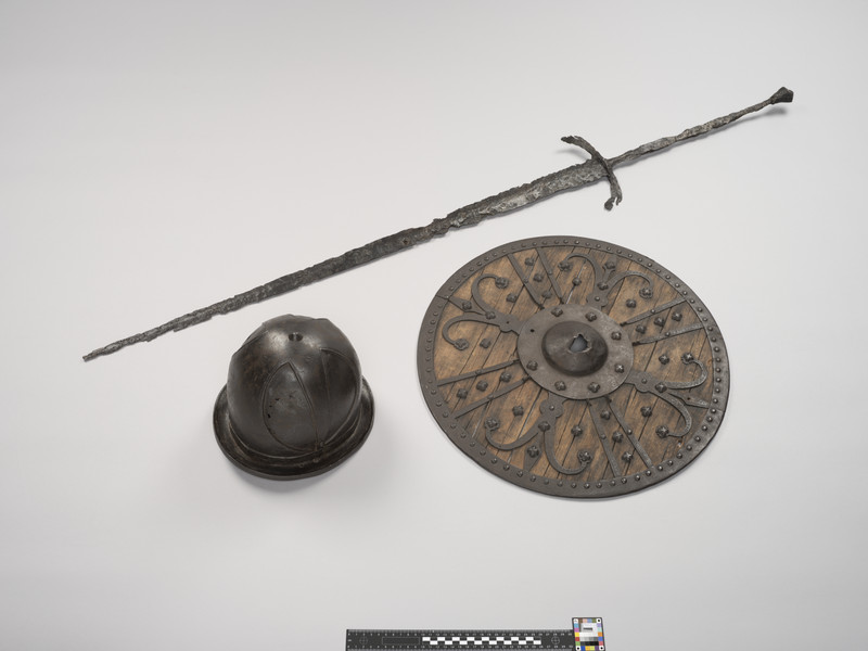 Hjelm av jern. Skjold av jern og tre. Sverd av jern og messing.