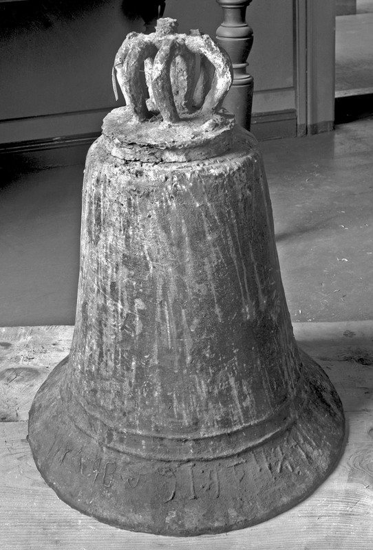 B 6102 Fra protokoll: "Kirkeklokke fra Sandeid kirke, Vikedal pgd. Stavanger amt, 55 cm. høi, hvorav bøilene utgjør 11,5 cm., og 43,5 cm. i tvermaal nederst. Simpelt støpt og saagodtsom ikke avpudset efter støpningen. Det eneste ornamentale utstyr er to omløpende ophøiete linier like over den utskytende rand. Langs randen er en indskrift, støpt bakvendt og meget skjødesløs i tegningen; den dannes dels av runer dels av majuskler: (runer) (Svæin prestr let gera mik). Klokken nævnes av N. Nicolaysen: Norske Fornl. s. 334; O. Ryghs oversættelse av indskriften er gjengit av L. Dietrichson: De norske Stavkirker, s. 482. Avbildet fig. 10"